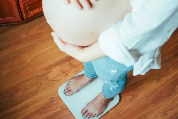 Image of woman weighing herself and experiencing weight gain through pregnancy New Scarborough